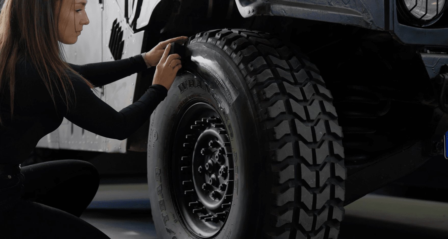 Frau reinigt reinen großen Reifen mit einem Schwamm