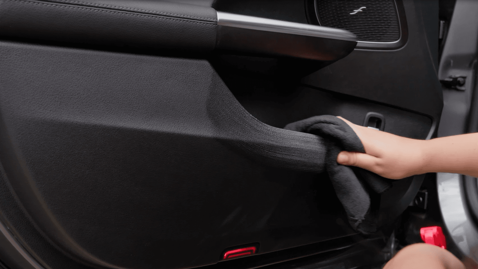 Kunststoffteil einer Autotür wird mit einem schwarzen Microfasertuch gereinigt.